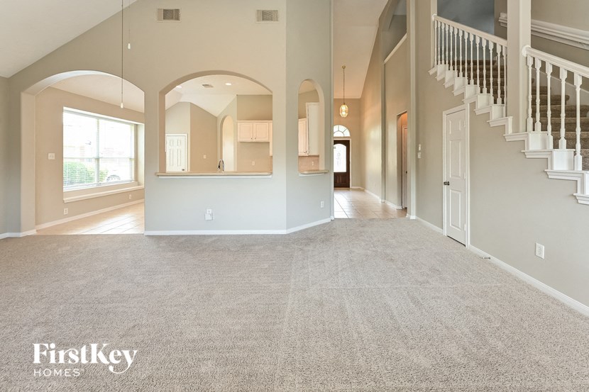 an empty living room with a staircase and a carpeted floor