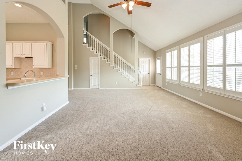 an empty living room with a staircase and a kitchen