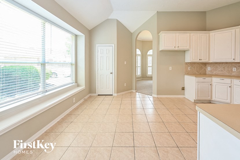 an empty kitchen with a large window and white cabinets