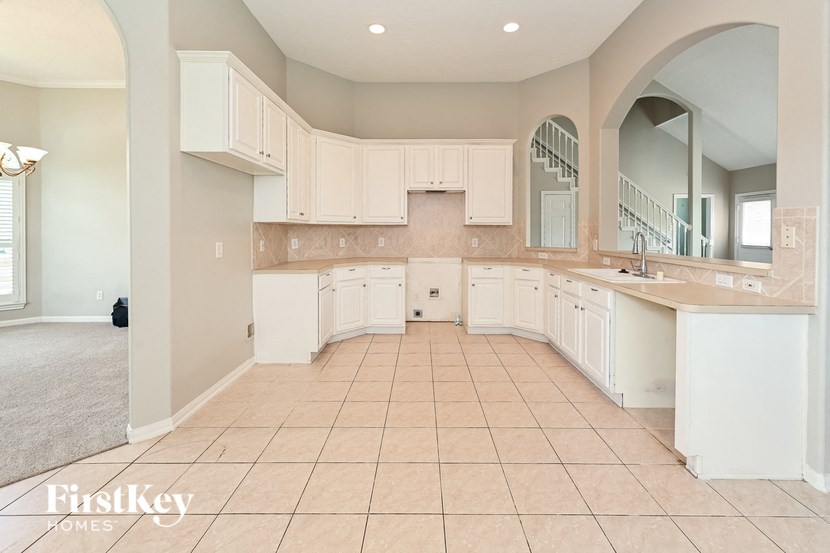 a large kitchen with white cabinets and tiled flooring