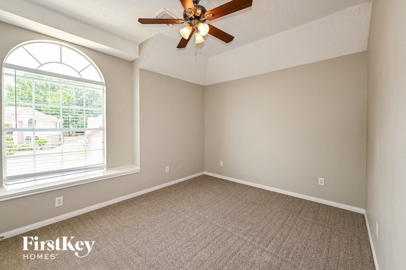 an empty living room with a ceiling fan and a large window