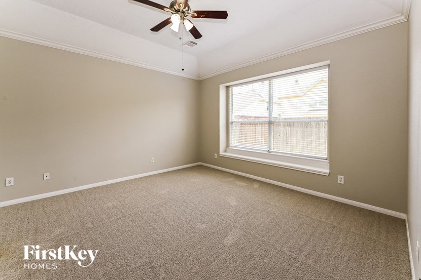 a bedroom with a large window and a ceiling fan