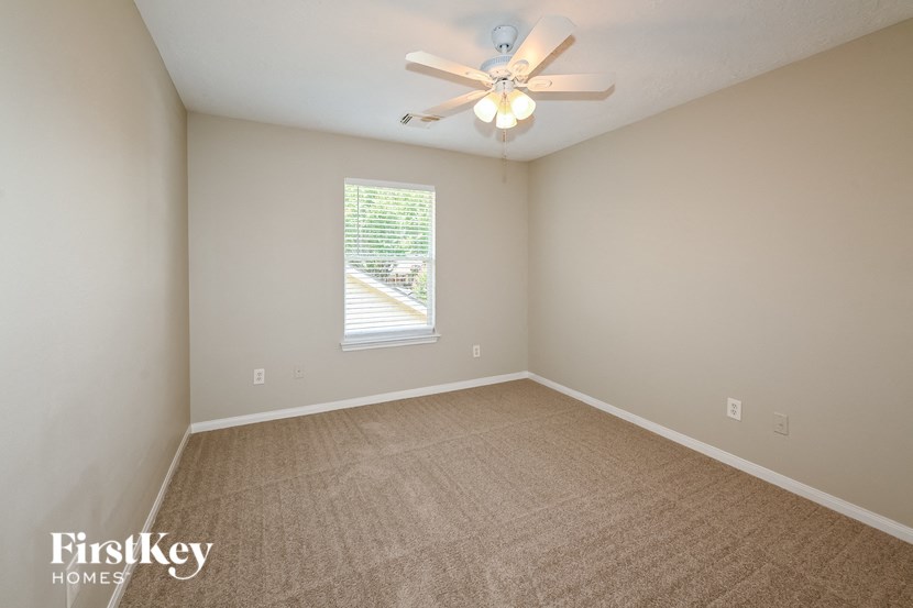 an empty living room with a ceiling fan and a window