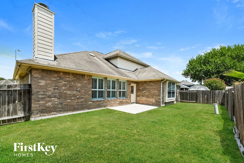 a backyard with a brick house and a lawn