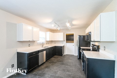 a black and white kitchen with white cabinets and black appliances