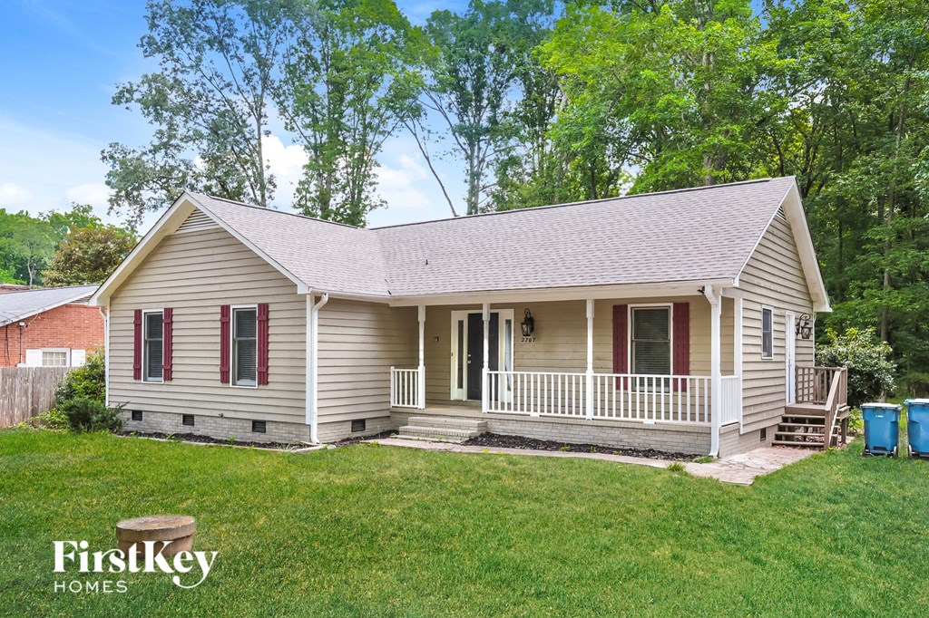 a small white house with a porch and a lawn