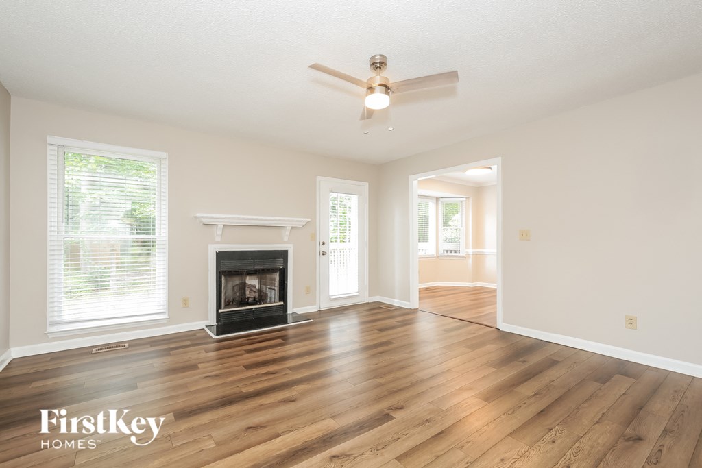 an empty living room with a fireplace and a ceiling fan