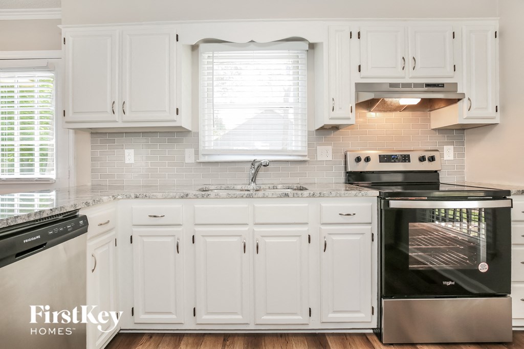 a white kitchen with white cabinets and black appliances