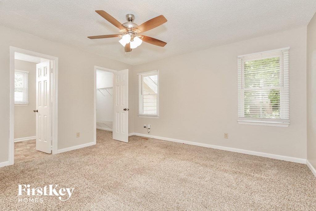 the spacious living room with ceiling fan and carpeting
