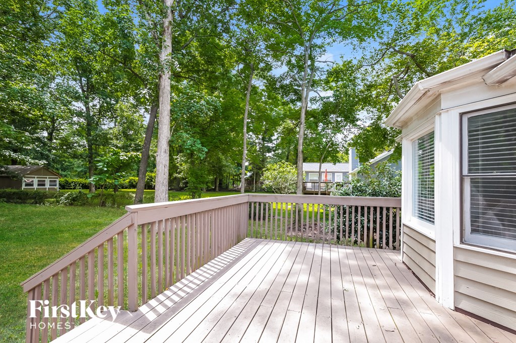 a deck with a view of the woods and a house