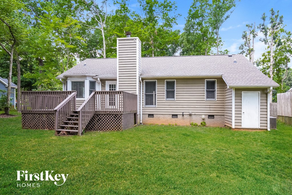 a small house with a deck and a yard with a fence