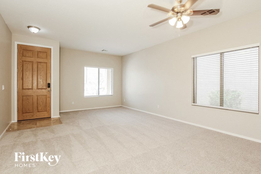 an empty living room with a wooden door and a ceiling fan
