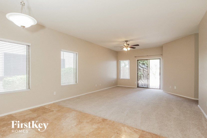 an empty living room with a ceiling fan and a window