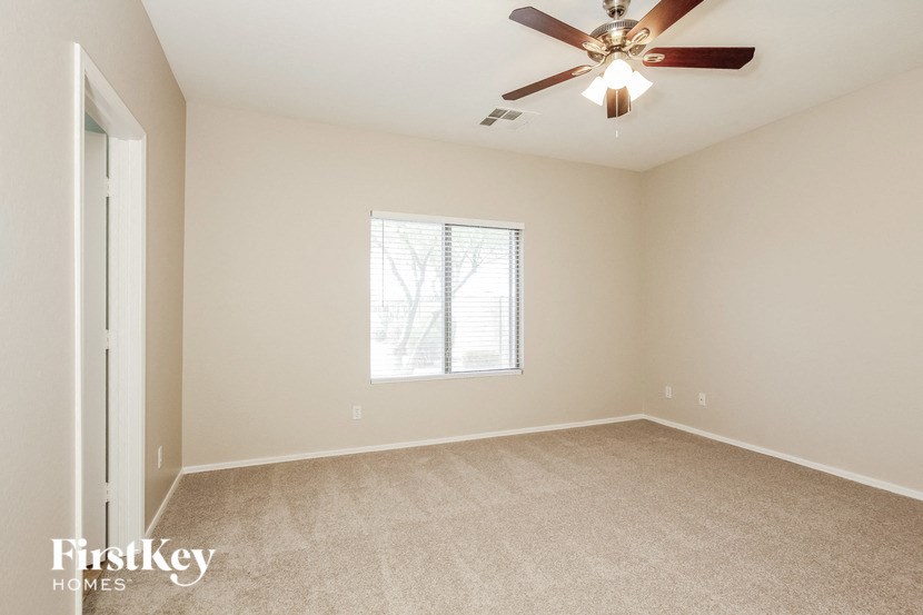 an empty living room with a ceiling fan and a window