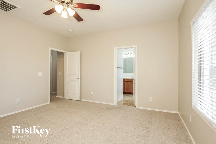 an empty living room with a ceiling fan and a door to a bathroom