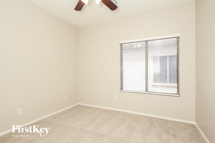an empty room with a window and a ceiling fan
