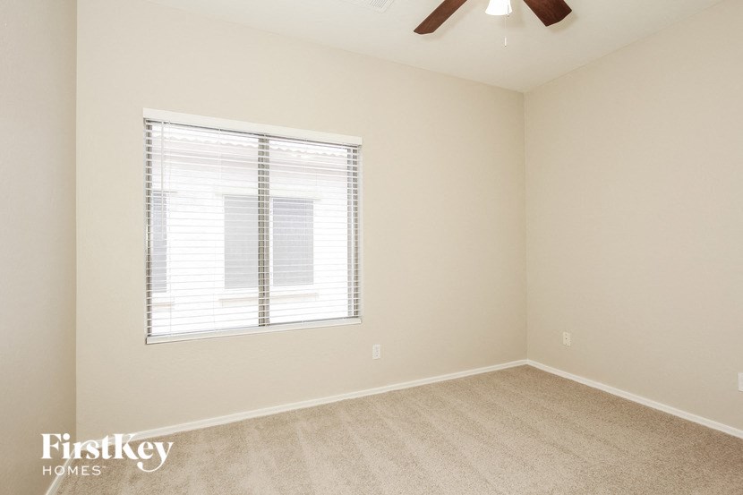 an empty room with a window and a ceiling fan