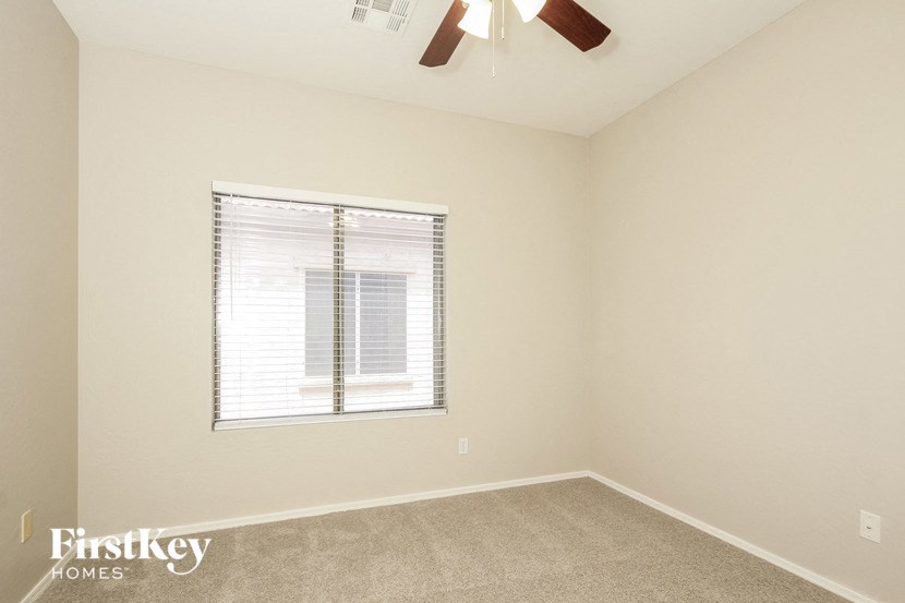 an empty room with a window and a ceiling fan