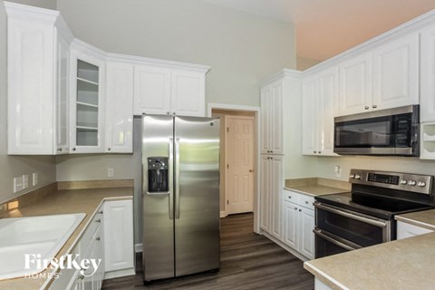 A kitchen with white cabinets and a stainless steel refrigerator.