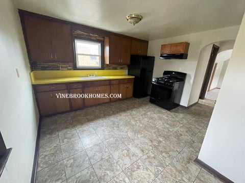 an empty kitchen with a yellow counter top and black appliances