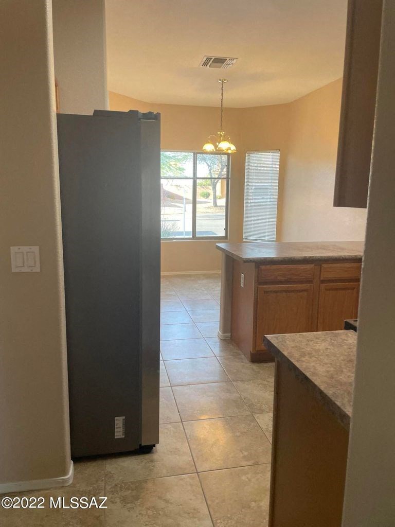 an empty kitchen with a black refrigerator in it