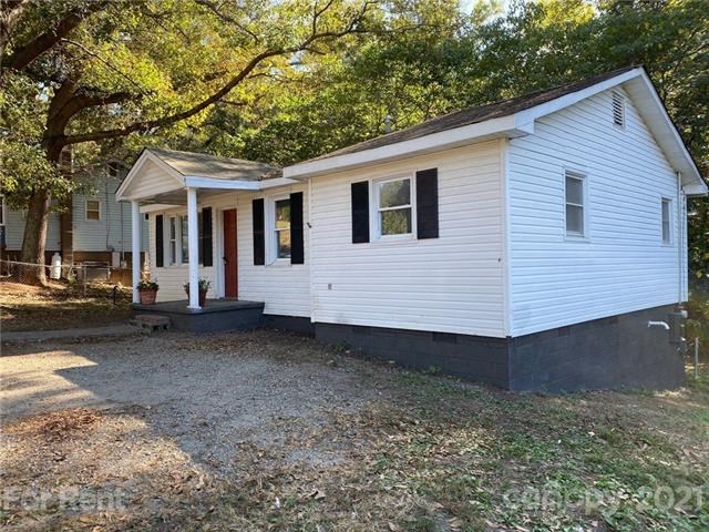 a small white house with a porch and some trees