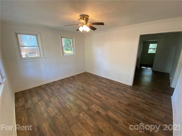an empty living room with a ceiling fan and wood floors