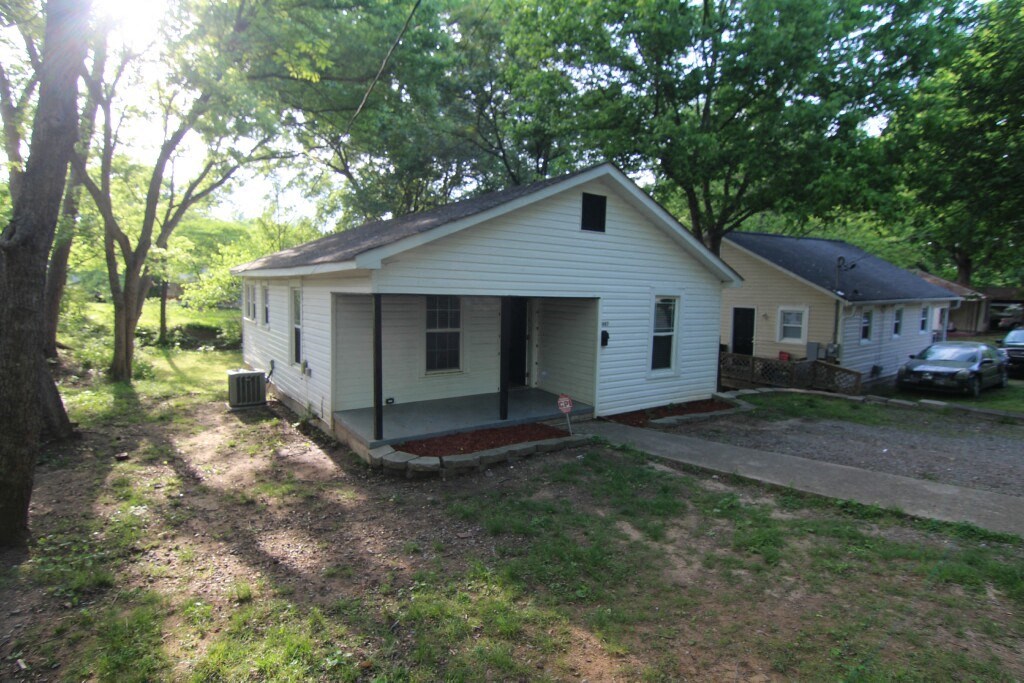 a small white house with a driveway and some trees