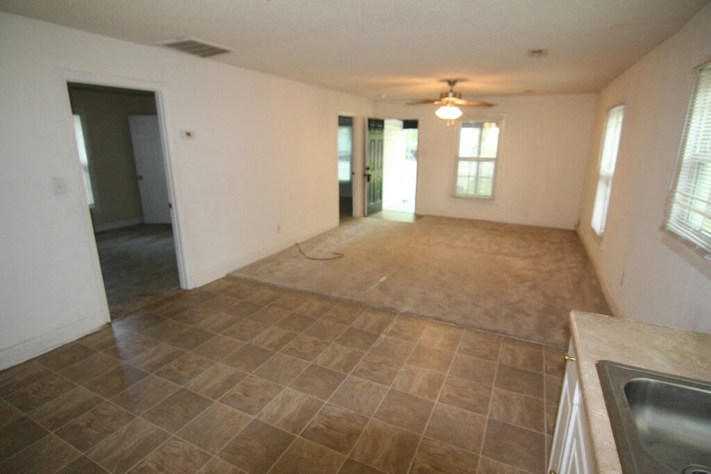 an empty kitchen and living room with a ceiling fan