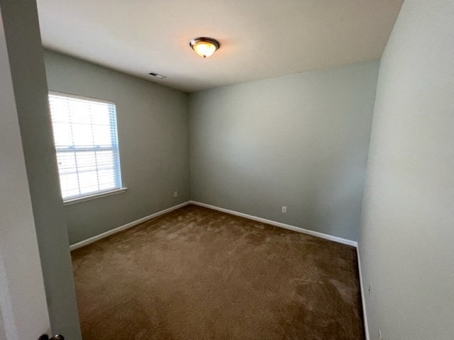 an empty room with a window and a carpet