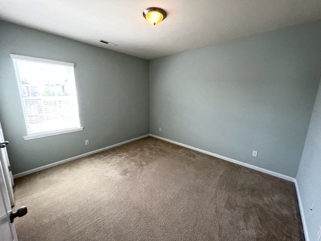 an empty blue room with a window and carpet