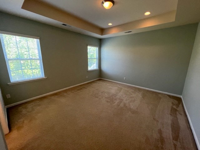 an empty room with a carpeted floor and two windows