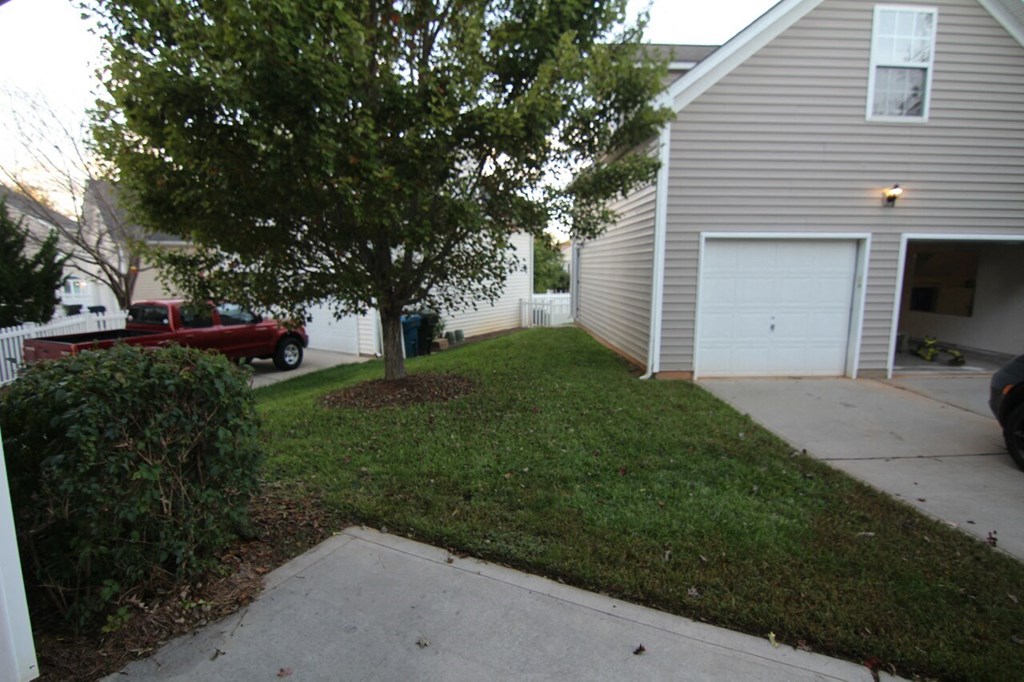 a yard in front of a house with a tree