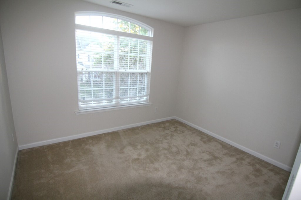 an empty room with a window and carpet