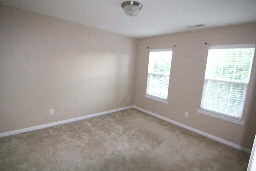 a room with a carpeted floor and two windows