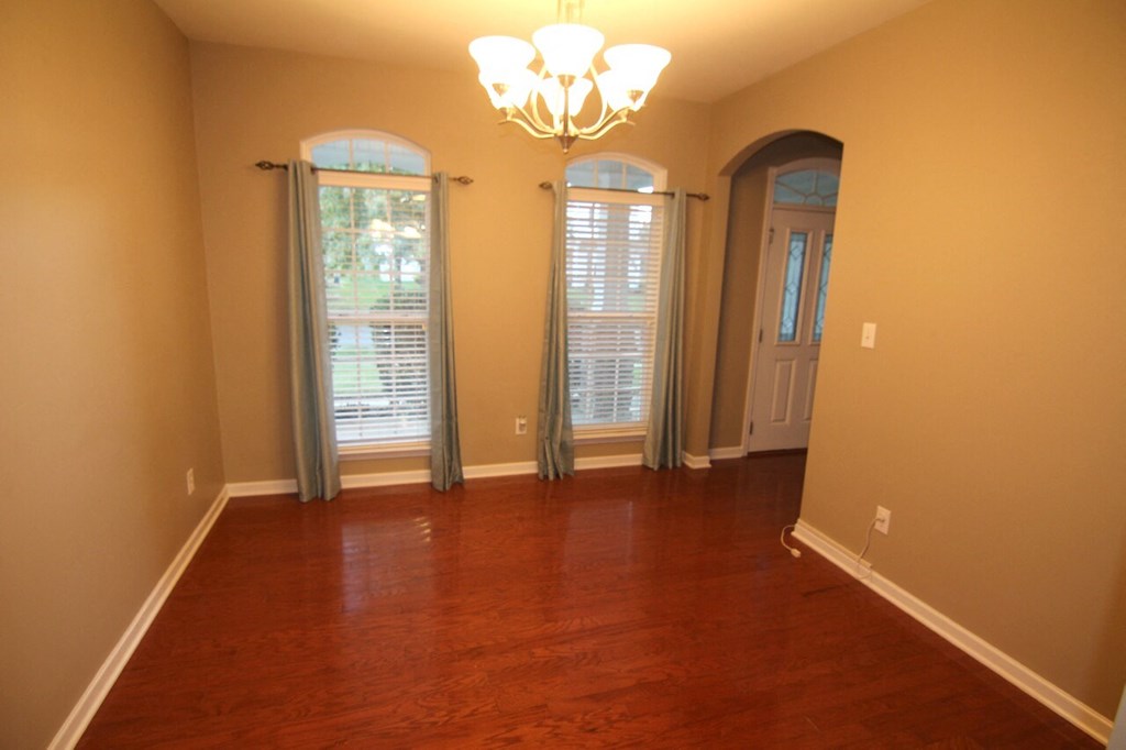 a empty living room with a wooden floor and windows