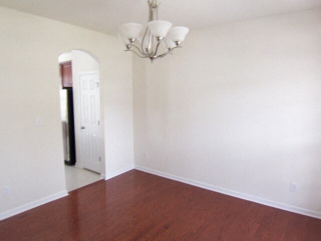 an empty room with a wooden floor and a chandelier
