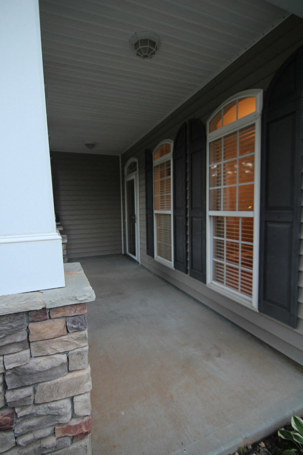 a covered porch with a stone wall and windows