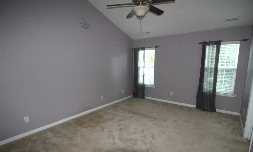 an empty living room with a ceiling fan and window