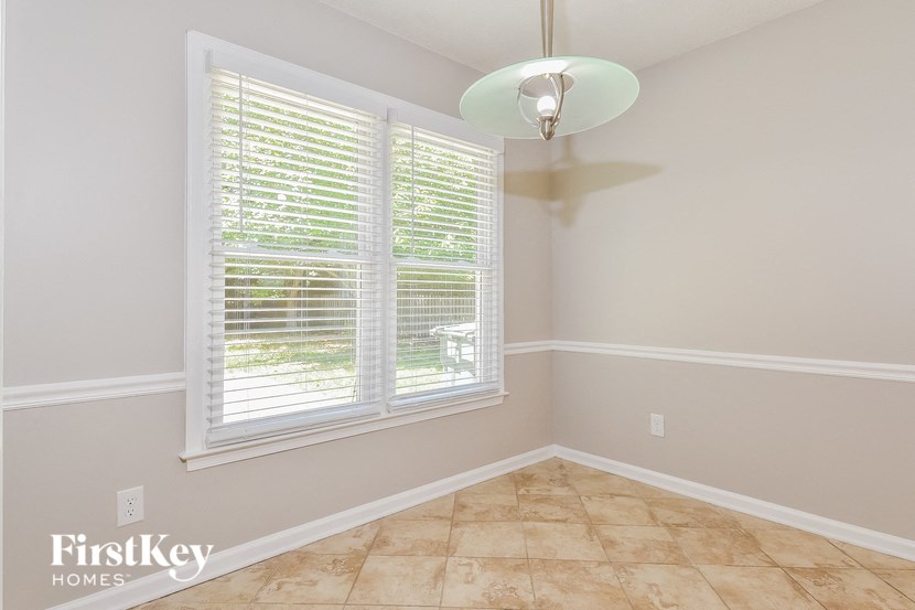 an empty dining room with a large window and a lamp