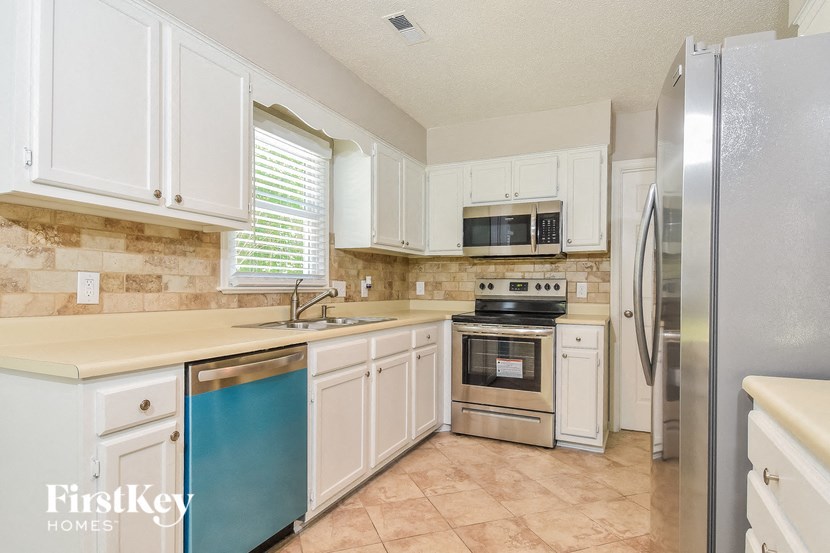 a kitchen with white cabinets and stainless steel appliances