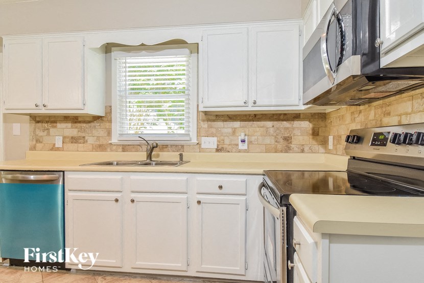 a kitchen with white cabinets and a sink and a window