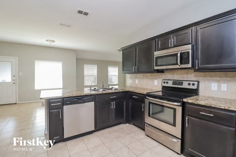 A kitchen with black cabinets and stainless steel appliances.
