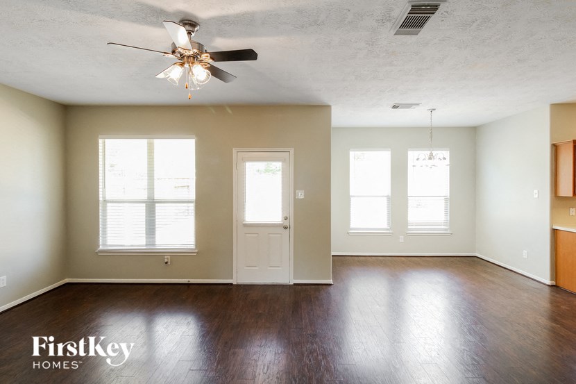 an empty living room with wood floors and a ceiling fan