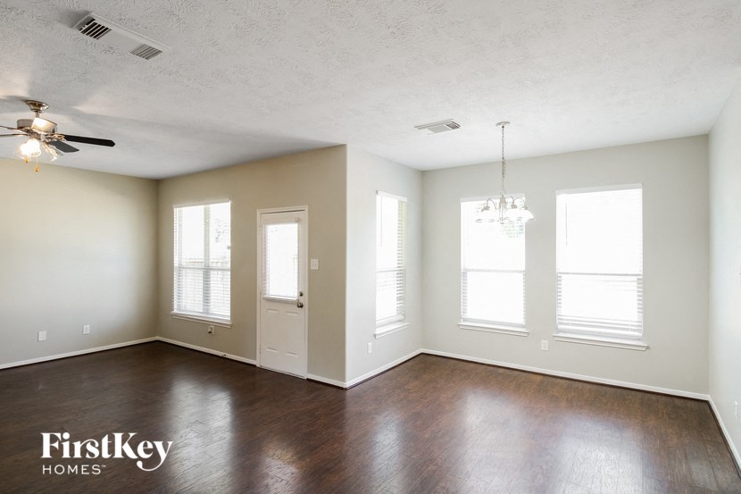 an empty living room with wood floors and a ceiling fan