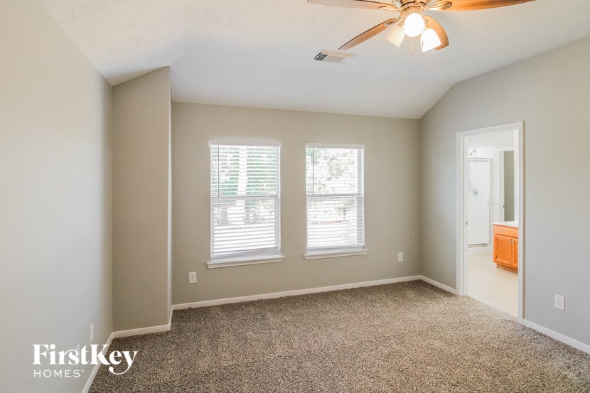 a bedroom with two windows and a ceiling fan