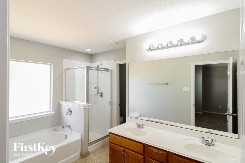 a white bathroom with a large mirror and a tub and shower