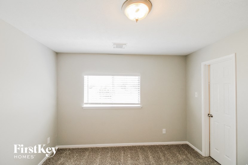 a bedroom with white walls and a window and a white door