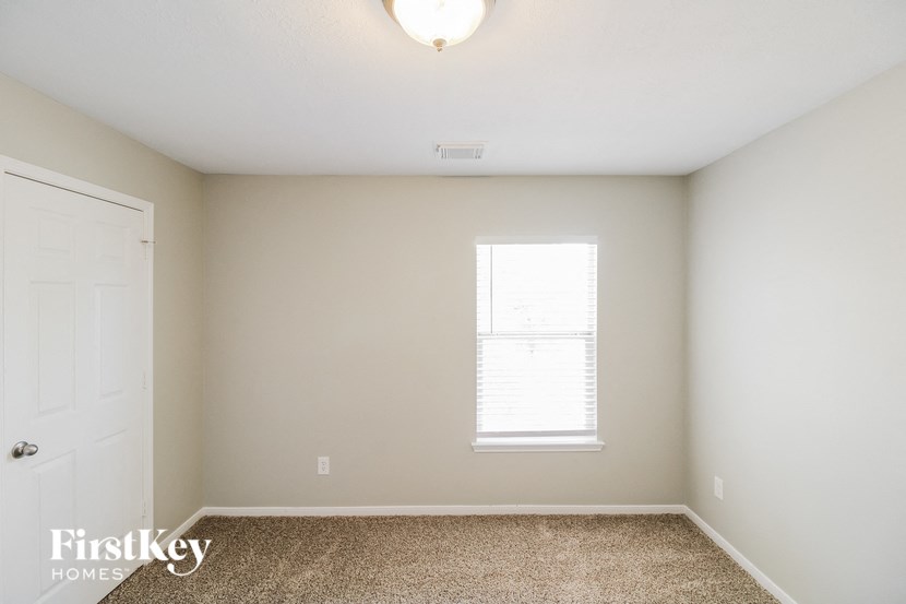 a bedroom with white walls and a window and a white door