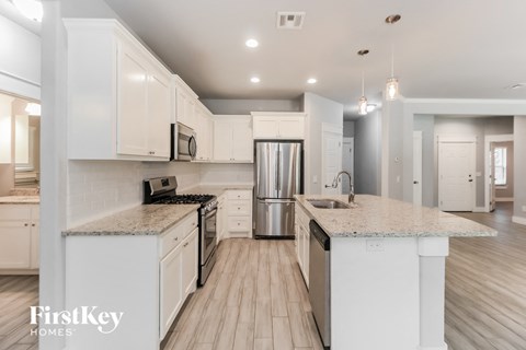 a kitchen with white cabinets and white counter tops and a stainless steel refrigerator